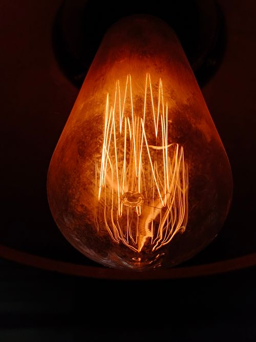 Free A close-up of a rustic glowing light bulb with intricate filament design, radiating warm light. Stock Photo