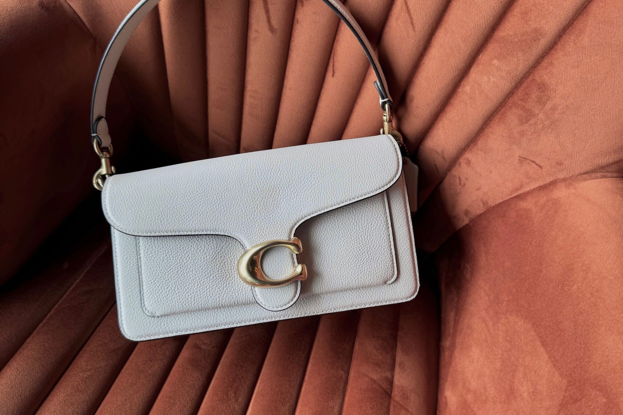 Tan leather bag resting on a vintage chair in warm light
