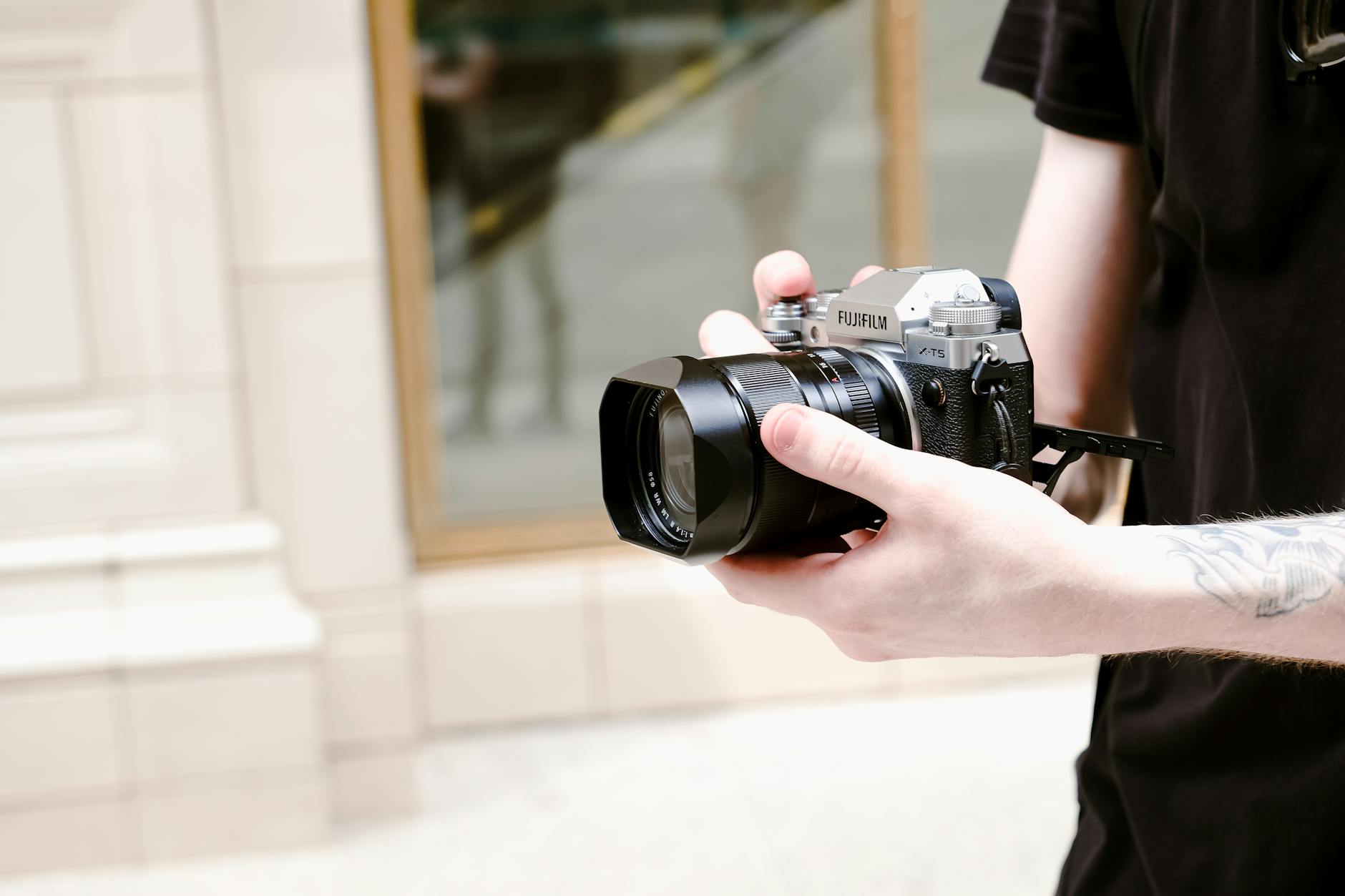 Outdoors close-up of hands holding a Fuji camera, focusing on modern photography.