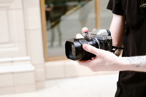 Free Outdoors close-up of hands holding a Fuji camera, focusing on modern photography. Stock Photo