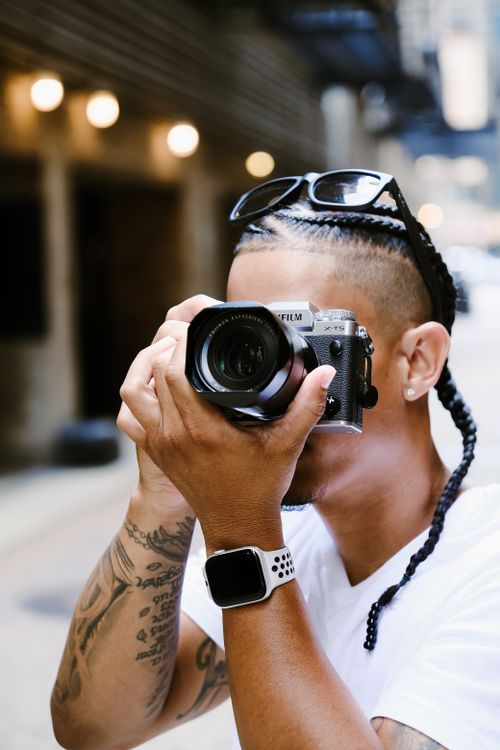 Free Young man with tattoos photographing city street scene outdoors. Stock Photo
