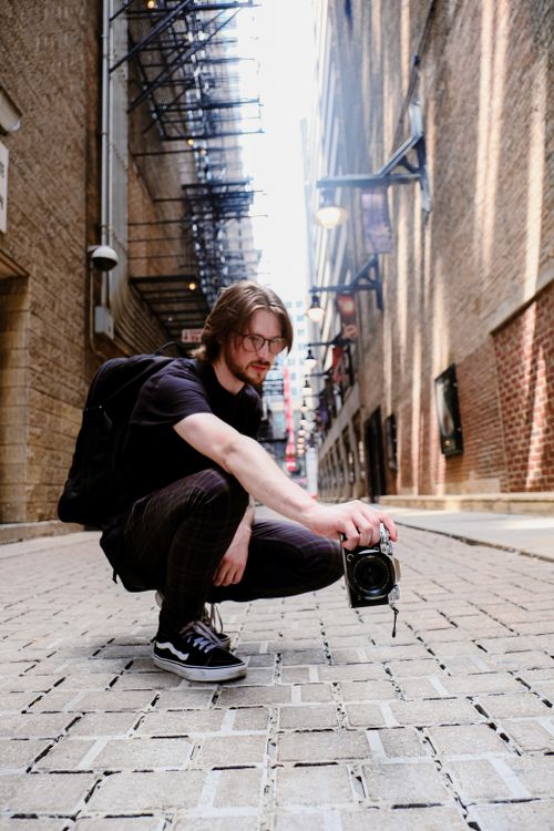 Free Young man photographing in an urban alley, showcasing street style and architecture. Stock Photo