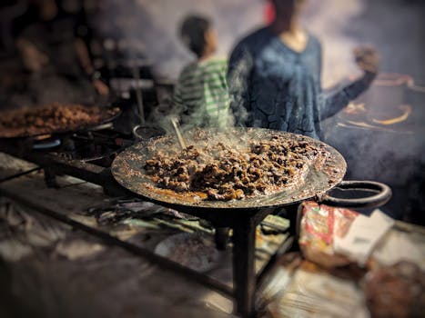 A vibrant scene of street food being grilled, showcasing sizzling meat on an open flame.