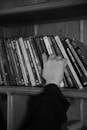 A person reaching for a book on a shelf