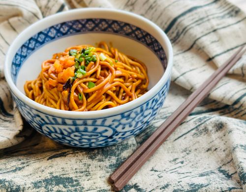 Free Delicious Asian noodles garnished with vegetables in a blue ceramic bowl on a rustic cloth. Stock Photo