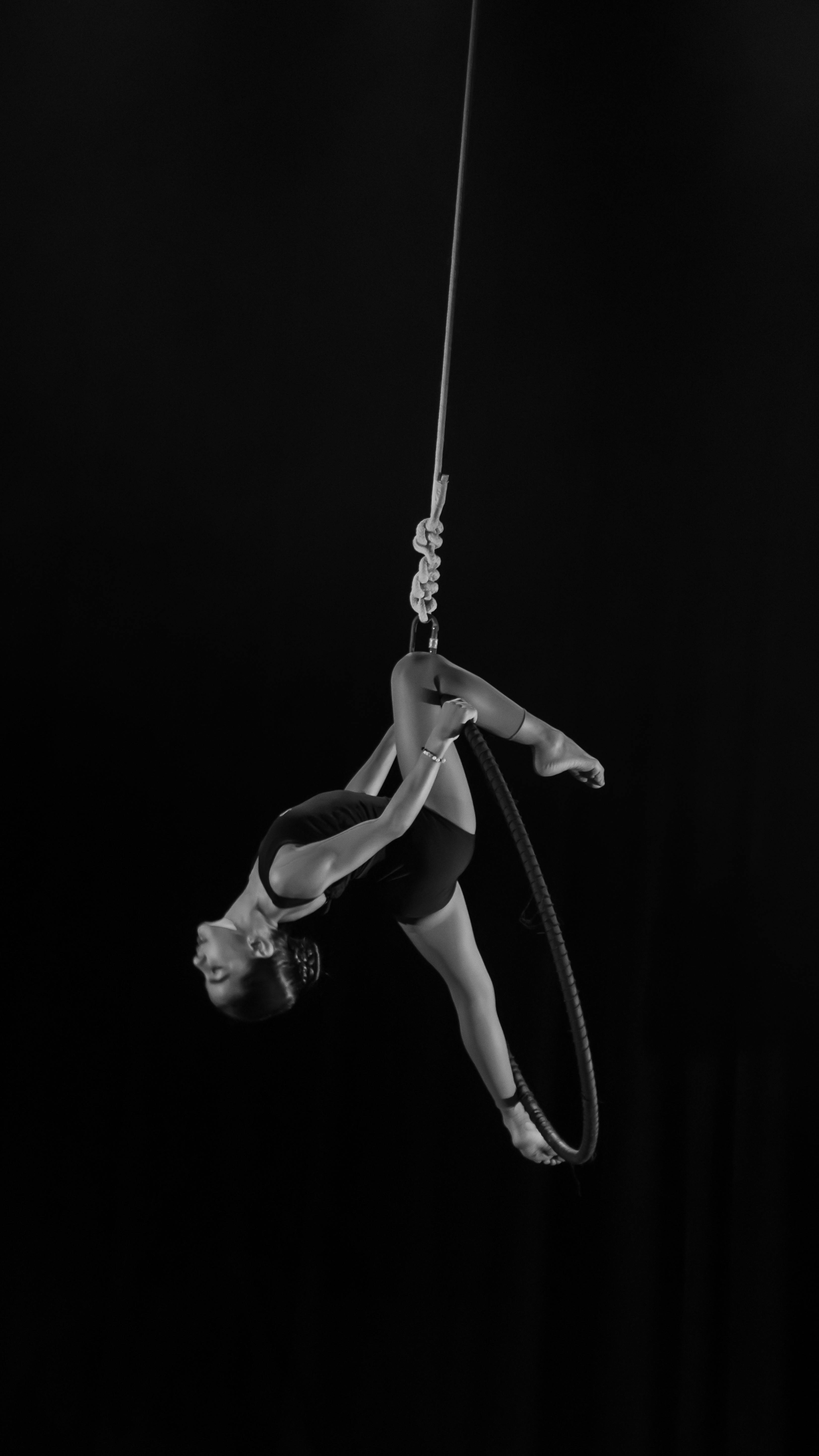 a black and white photo of a woman hanging on a rope