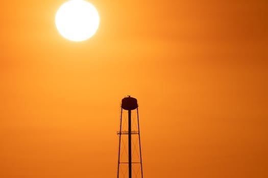A striking sunset silhouette of a water tower against a vivid orange sky in Mather, CA.