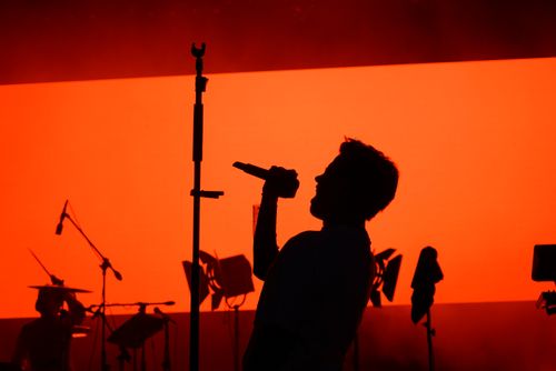 Silhouette of a singer performing under red stage light — photo by Bunyamin Cicek on Pexels