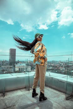 Trendy woman in sunglasses posing on a rooftop in Mexico City with urban skyline backdrop.