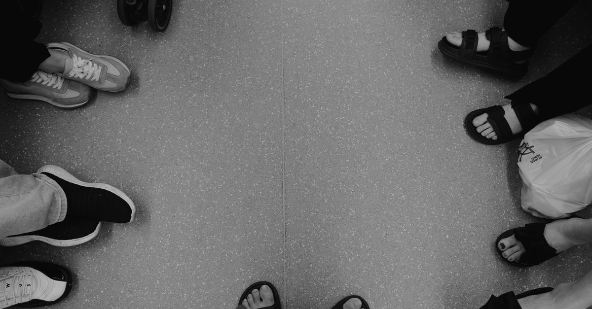 Black and white photo showcasing diverse footwear on a public transit floor.