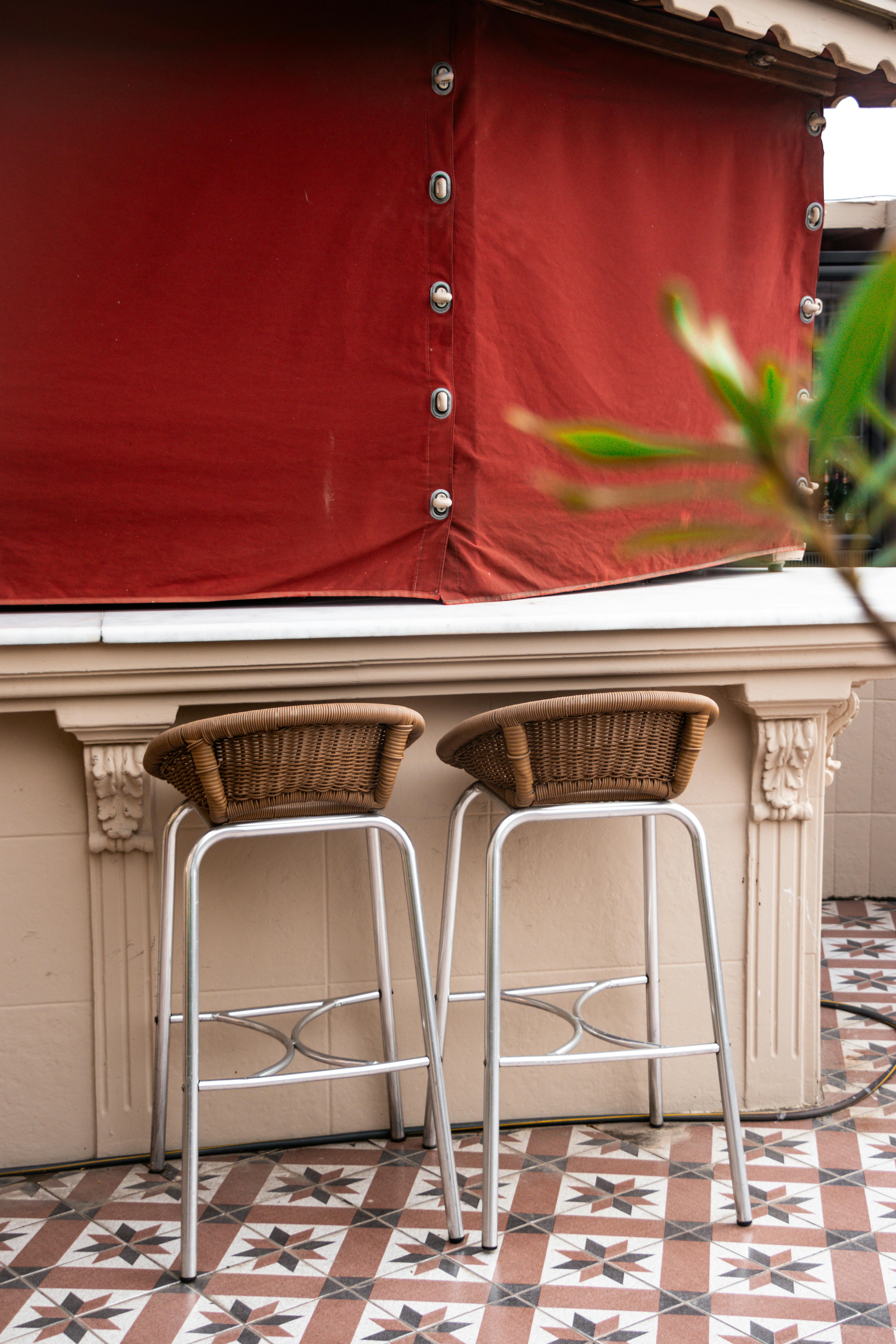 two stools are sitting on a patio with a red curtain