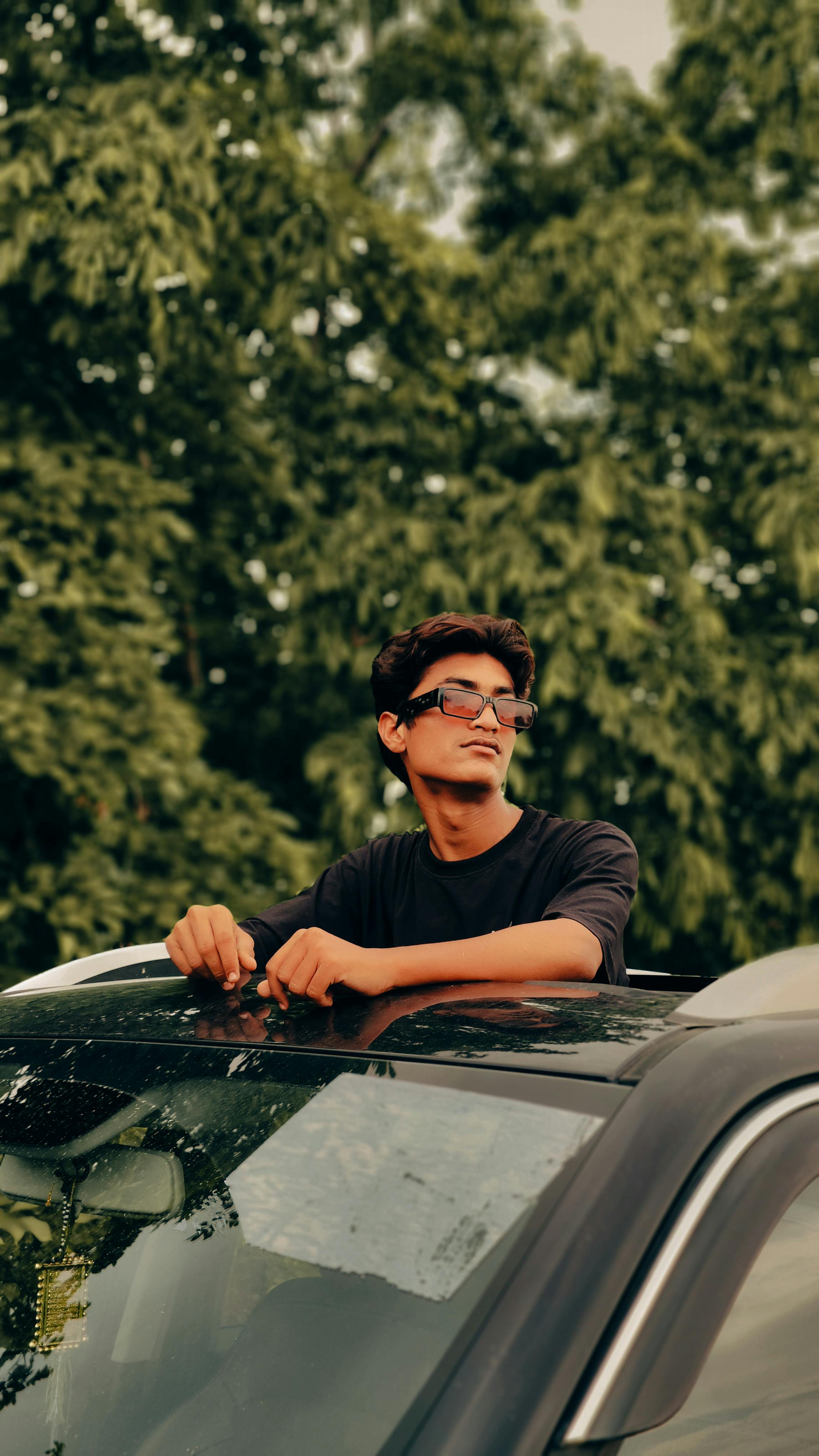 a man sitting on top of a car with sunglasses