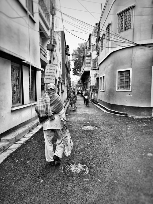 Free Black and white image of people walking in a narrow street in Kolkata, India. Stock Photo
