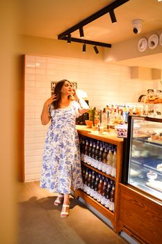 Woman in a floral dress enjoying a modern cafe setting with luxury ambiance.