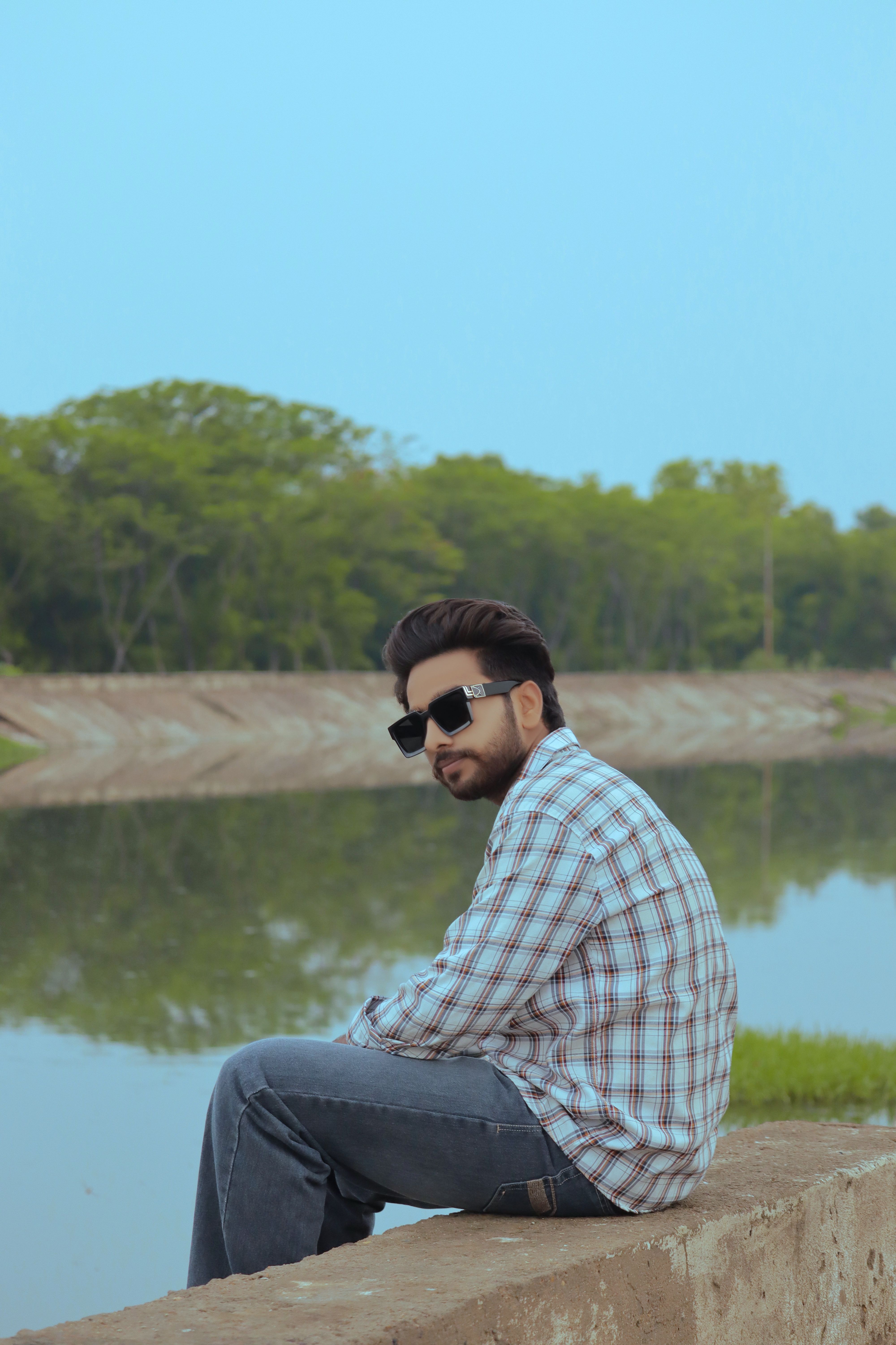 A man enjoying leisure time by a calm lake, surrounded by lush greenery.