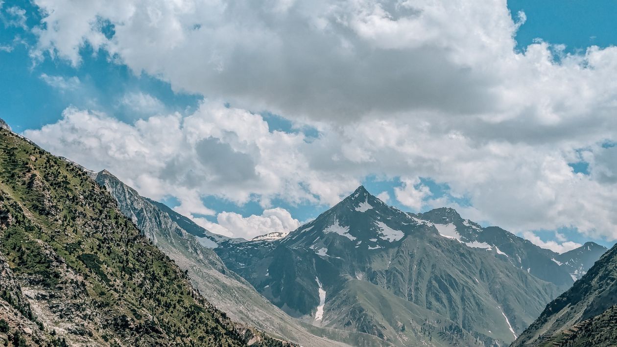 A mountain range with clouds and blue sky · Free Stock Photo