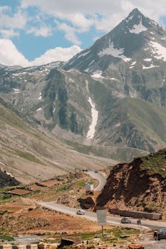 Scenic view of a mountain landscape with a winding road under a bright blue sky.