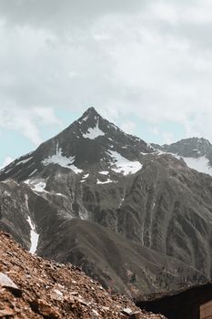 Majestic snow-capped mountain peak under a cloudy sky, showcasing natural beauty and serene landscapes.
