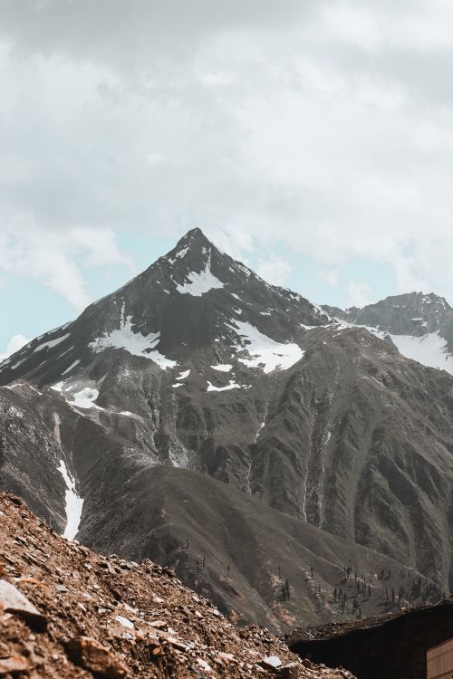 Free Majestic snow-capped mountain peak under a cloudy sky, showcasing natural beauty and serene landscapes. Stock Photo