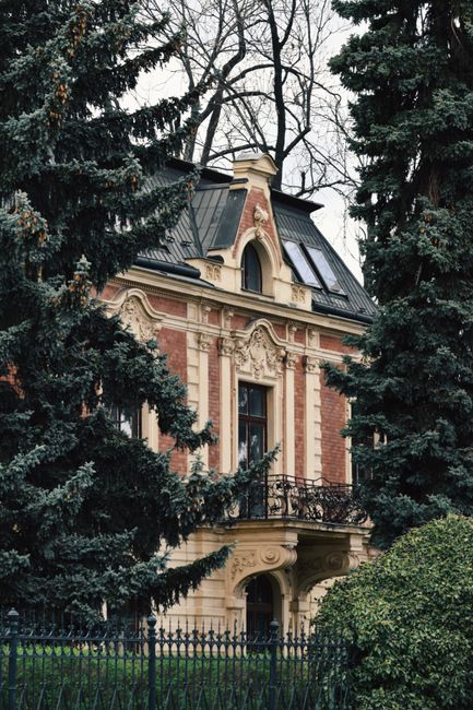 Charming Victorian-style mansion surrounded by lush trees, showcasing architectural beauty.