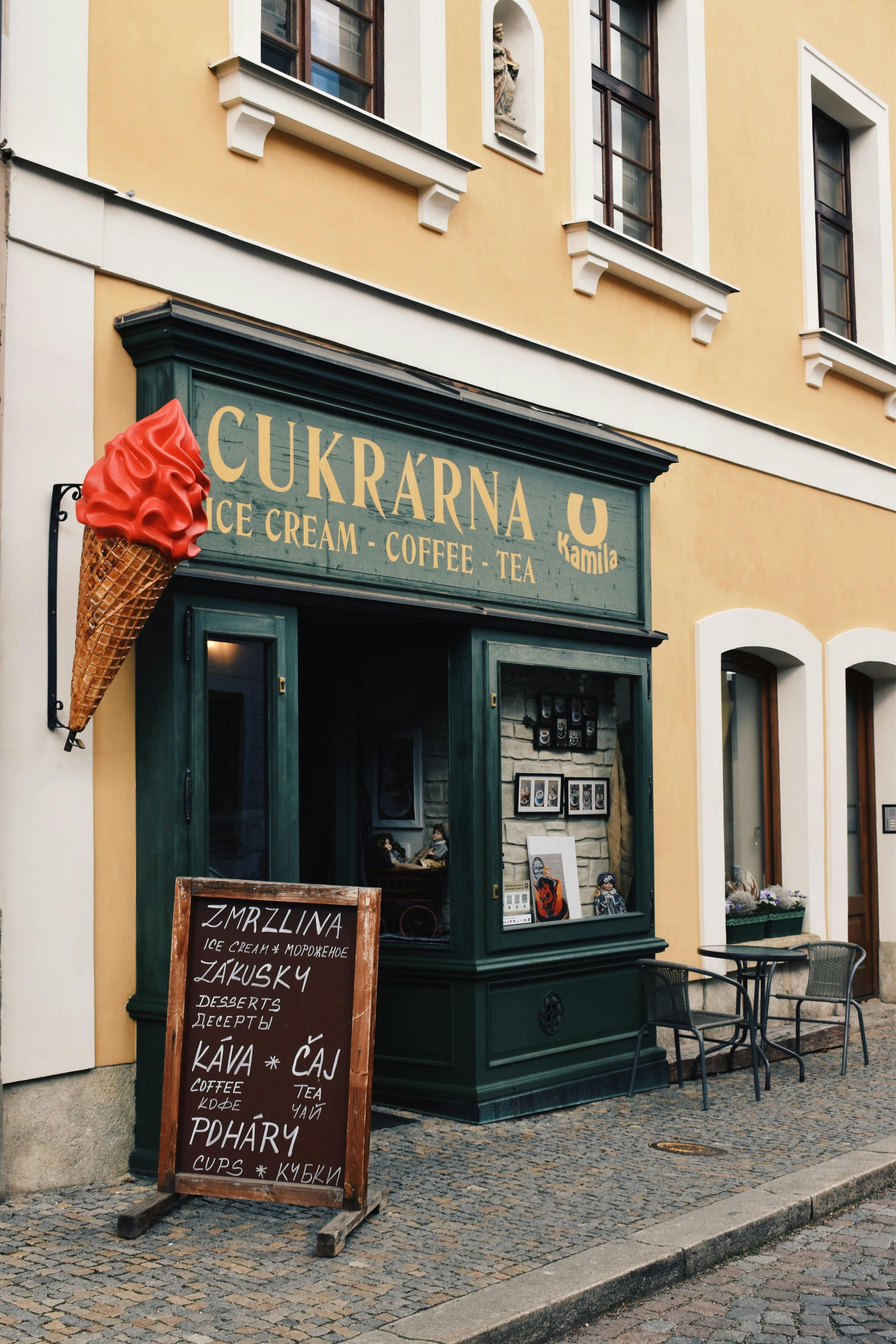 Vintage ice cream cafe facade with outdoor seating on cobblestone street.