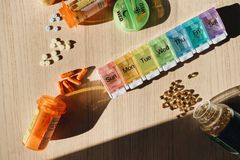 Colorful pill organizer with medication bottles and tablets on a wooden surface.