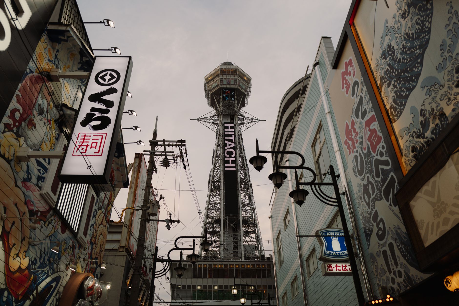 View of Osaka's Tsutenkaku Tower amidst colorful street art and urban architecture, a blend of tradition and modernity.