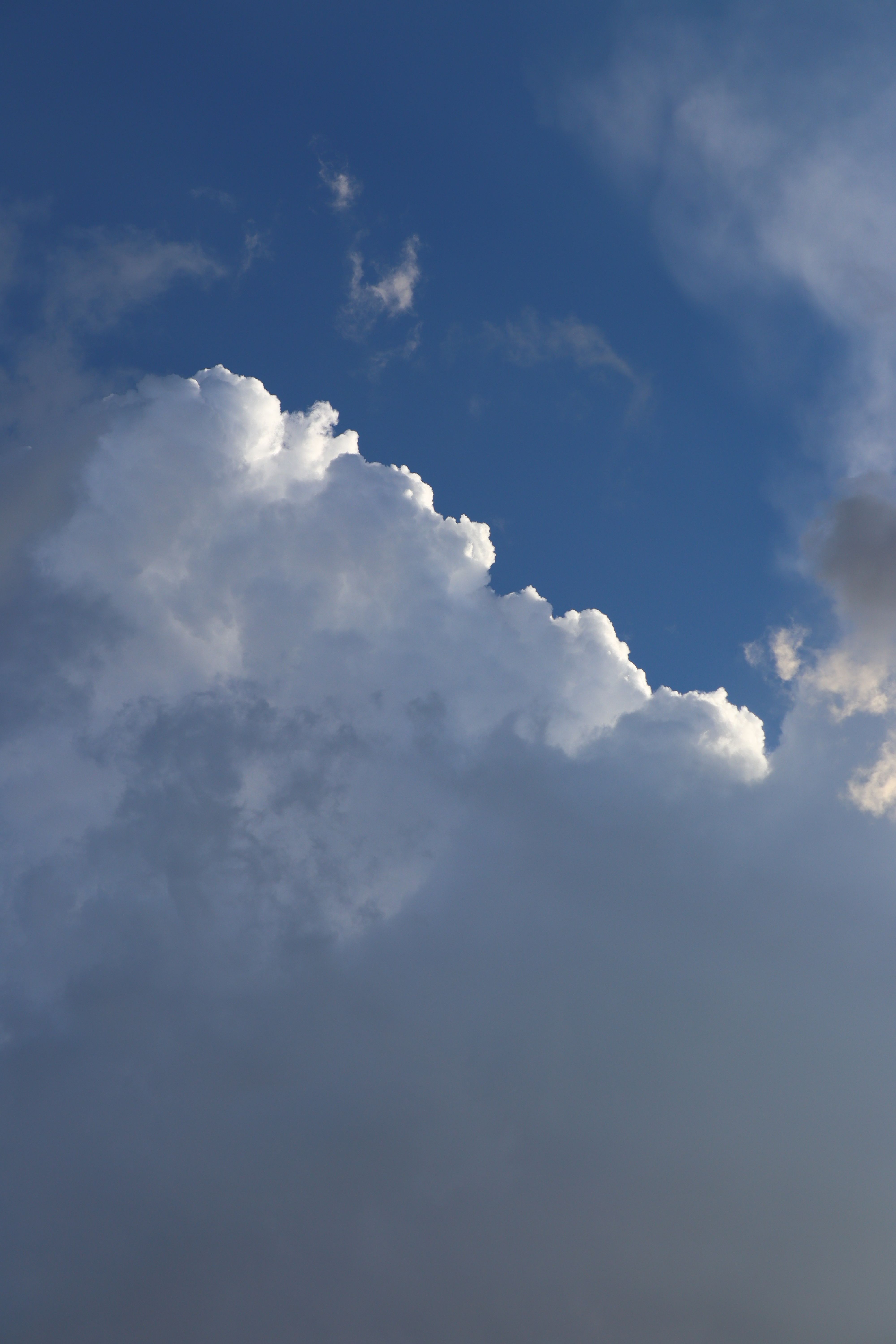 A plane flying through a cloudy sky with some clouds · Free Stock Photo