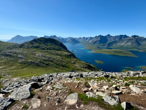 Free Stunning panoramic view of rugged mountains and serene lake under clear summer sky. Stock Photo