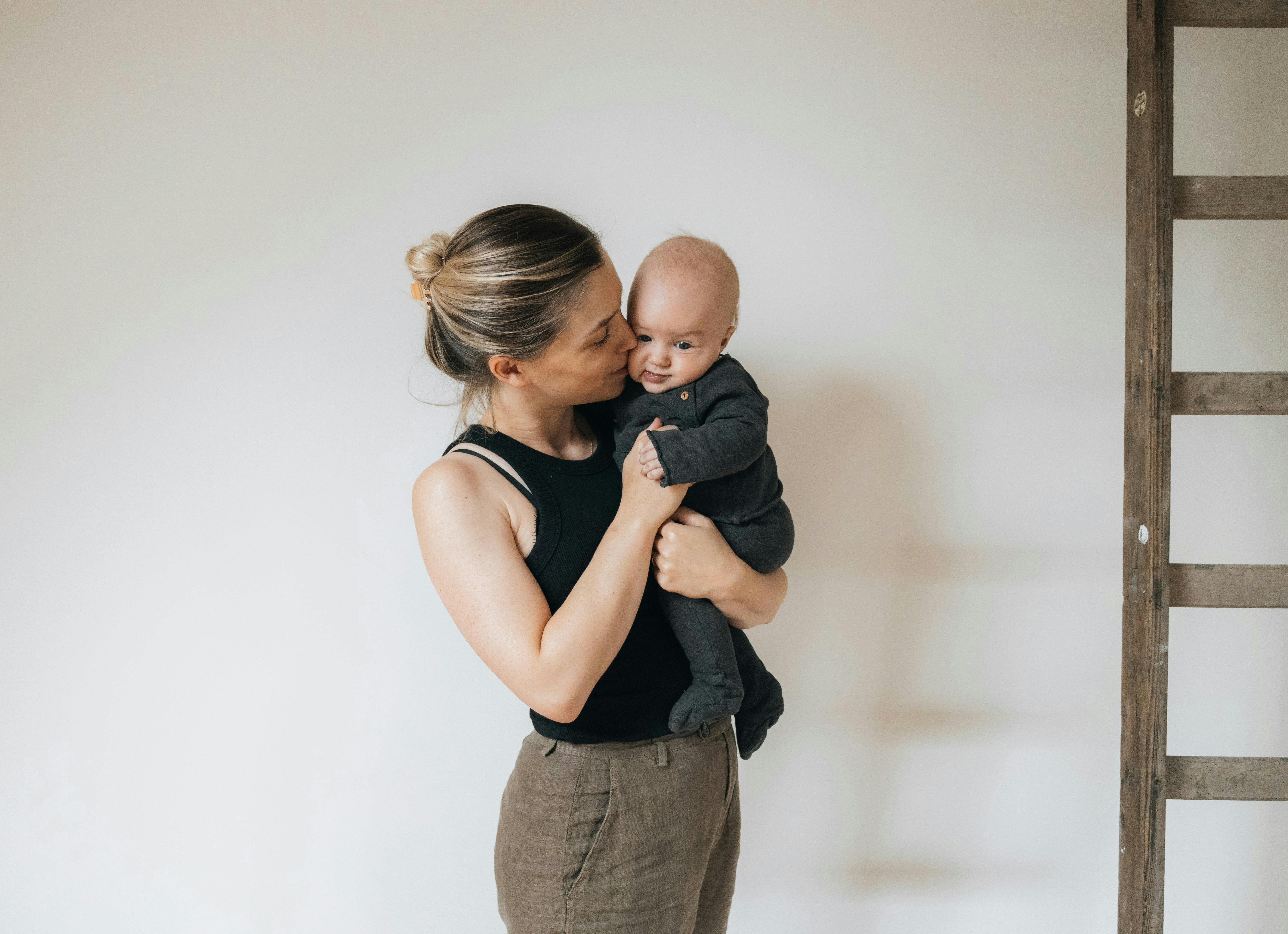 a woman holding a baby in front of a ladder