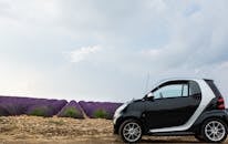 一辆智能汽车停在夏日天空下，旁边是充满活力的薰衣草田，展现了自然美景与现代设计的融合