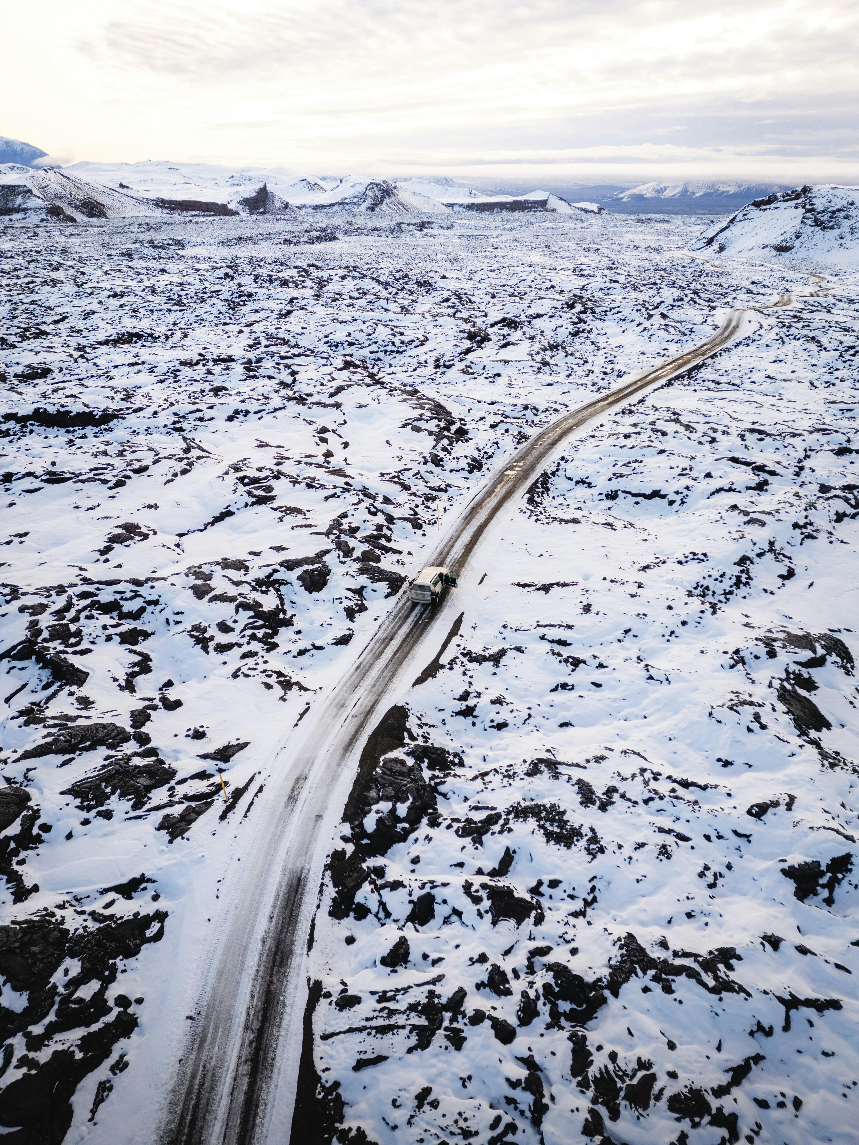 Drone shot capturing a winding road through the snowy landscape of Þingeyjarsveit, Iceland in winter.
