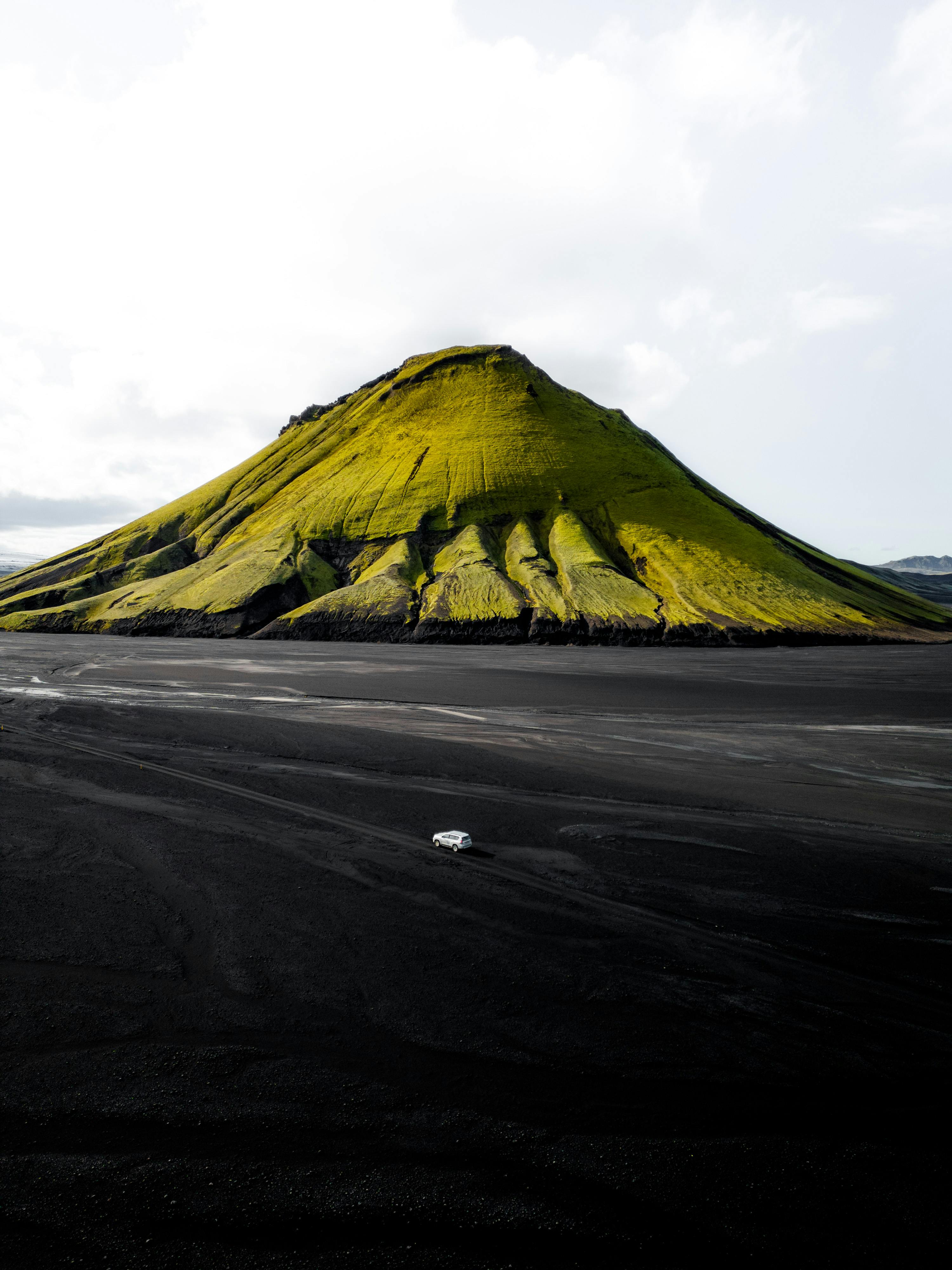 Stunning aerial shot of Maelifell Volcano, capturing its unique green slopes against the black desert backdrop.