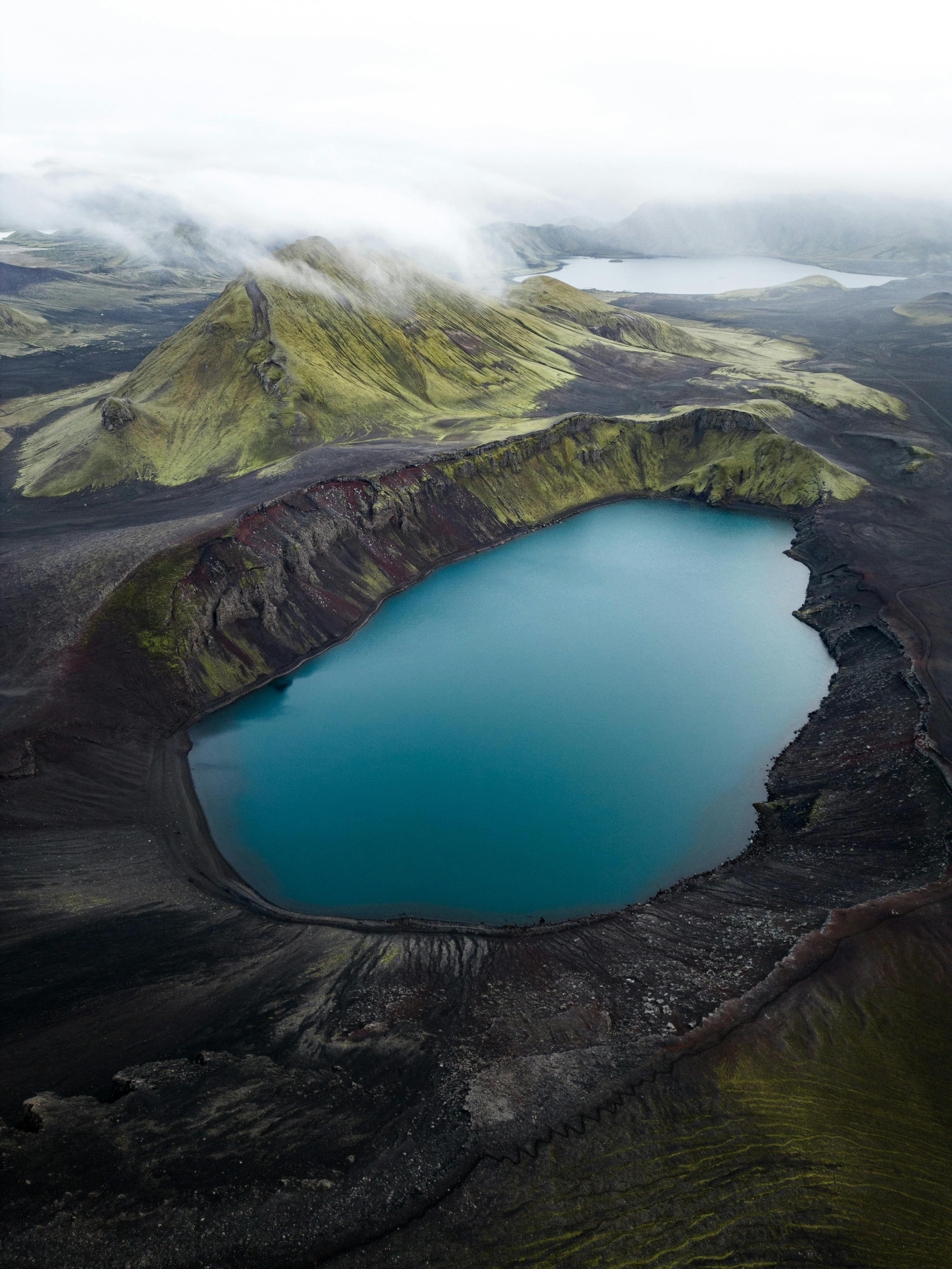 A stunning aerial view of Bláhylur, a vibrant blue crater lake surrounded by rugged Icelandic landscapes.