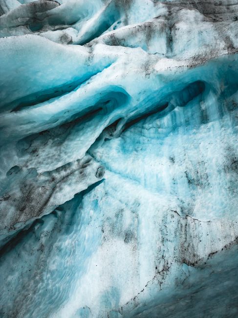 A detailed aerial view showcasing intricate glacier patterns and melting ice with vivid blue tones.