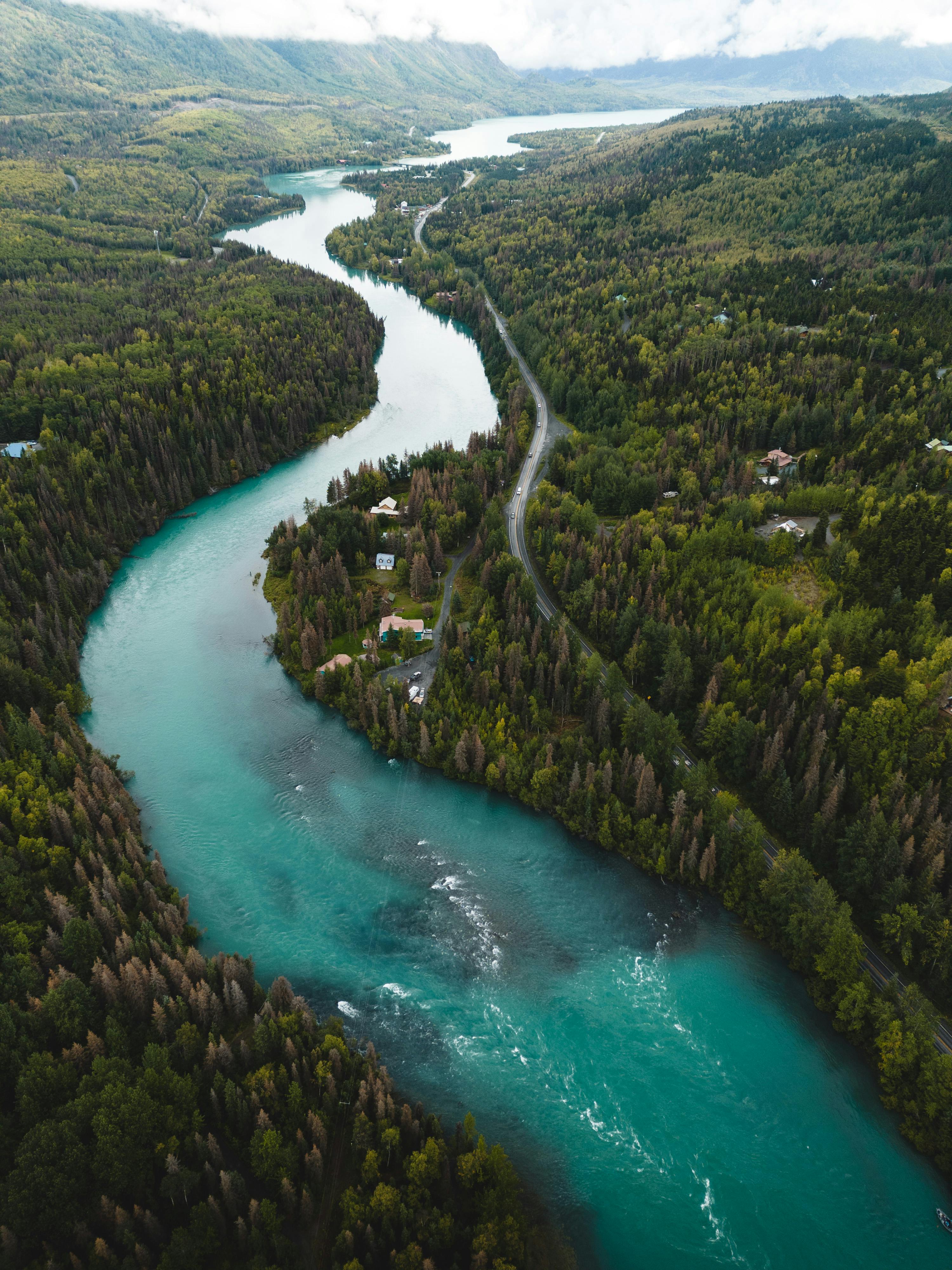 A stunning aerial view of the vibrant Kenai River winding through dense forests in Cooper Landing, Alaska.
