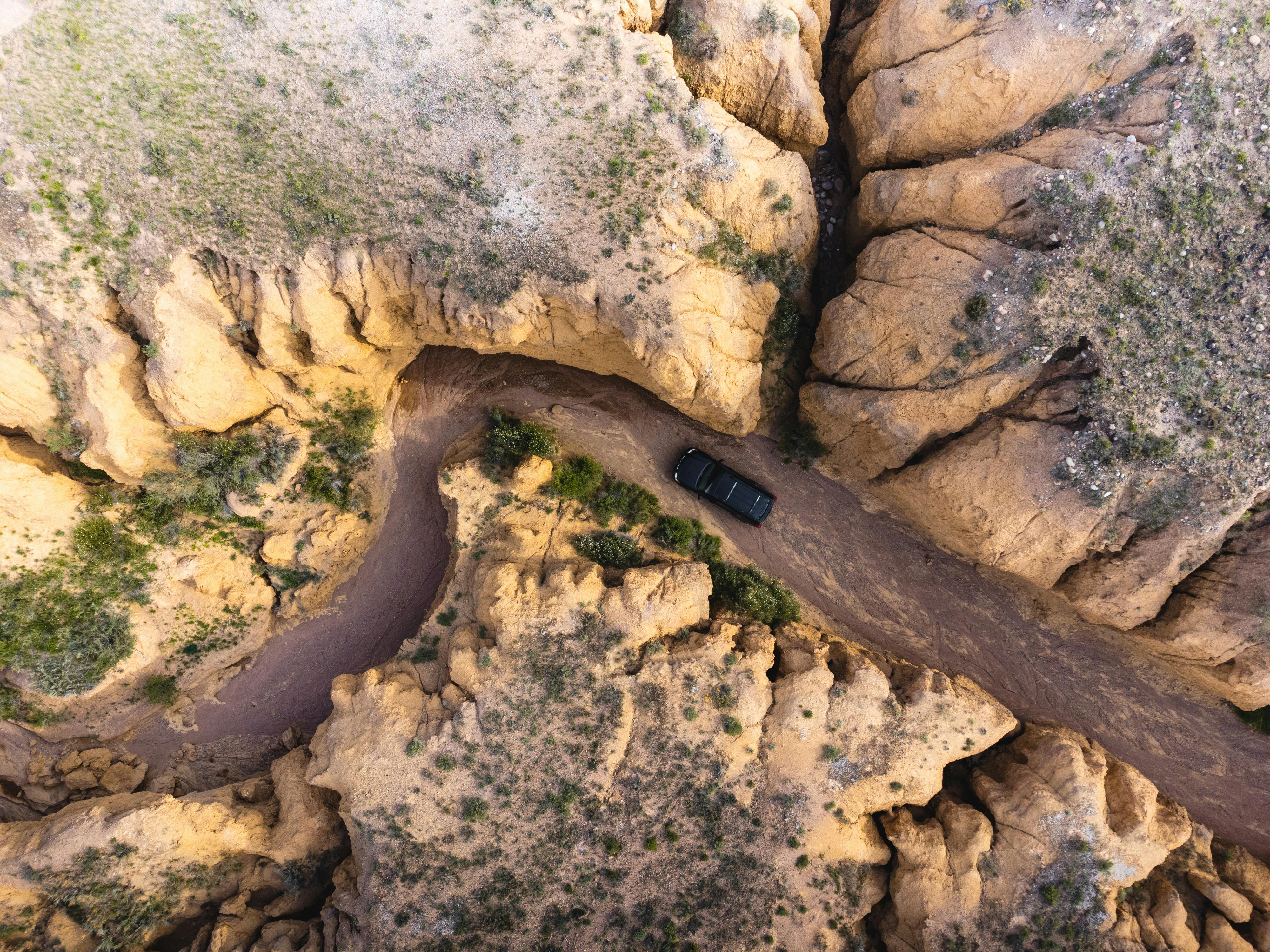 an aerial view of a car driving down a dirt road