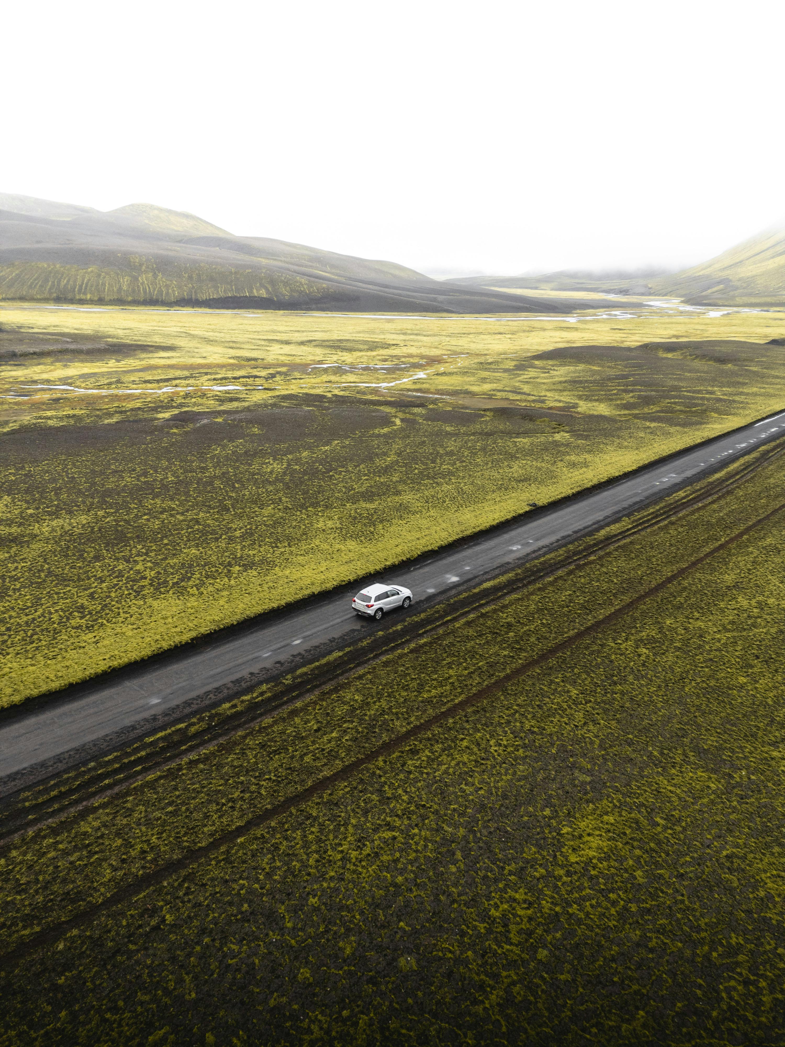 Aerial shot of a road cutting through scenic green landscapes in Iceland.