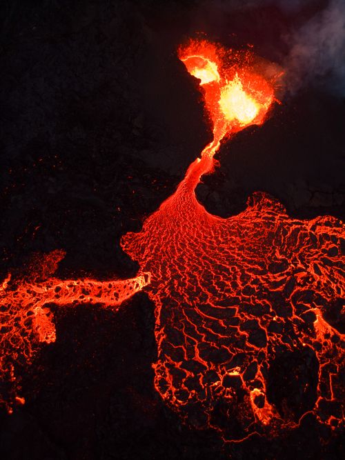 Free Dramatic aerial shot of bright red lava flowing from an active volcano at night. Captivating natural phenomenon. Stock Photo