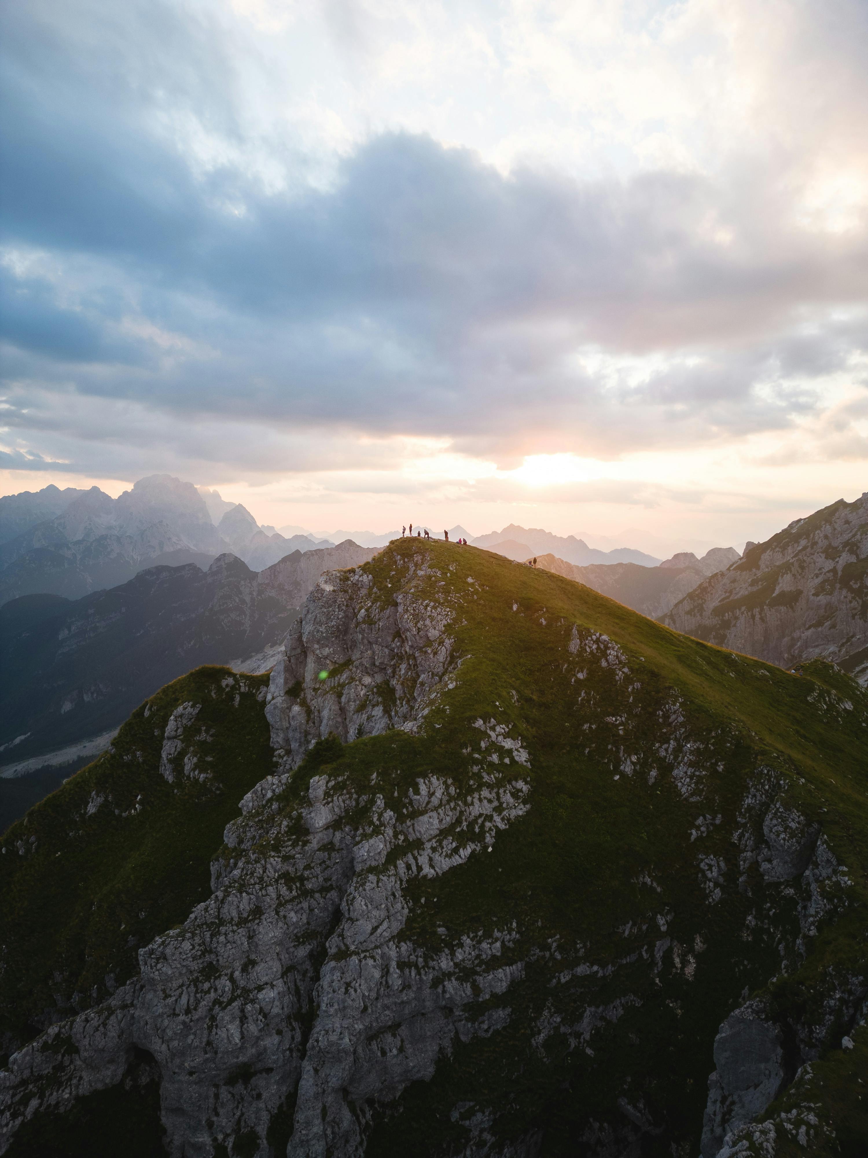 A breathtaking view of an Alpine mountain peak at sunset with a group of hikers.