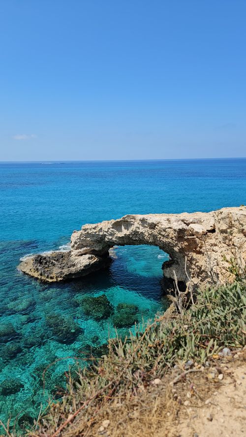 Free Captivating view of a natural rocky arch over turquoise waters under a clear sky. Stock Photo