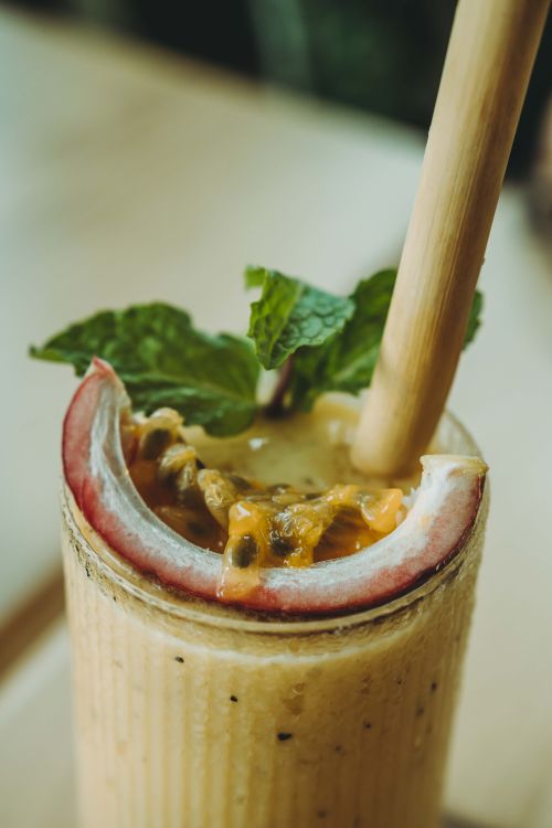 Free Close-up of a creamy passion fruit smoothie garnished with mint and served with a bamboo straw. Stock Photo