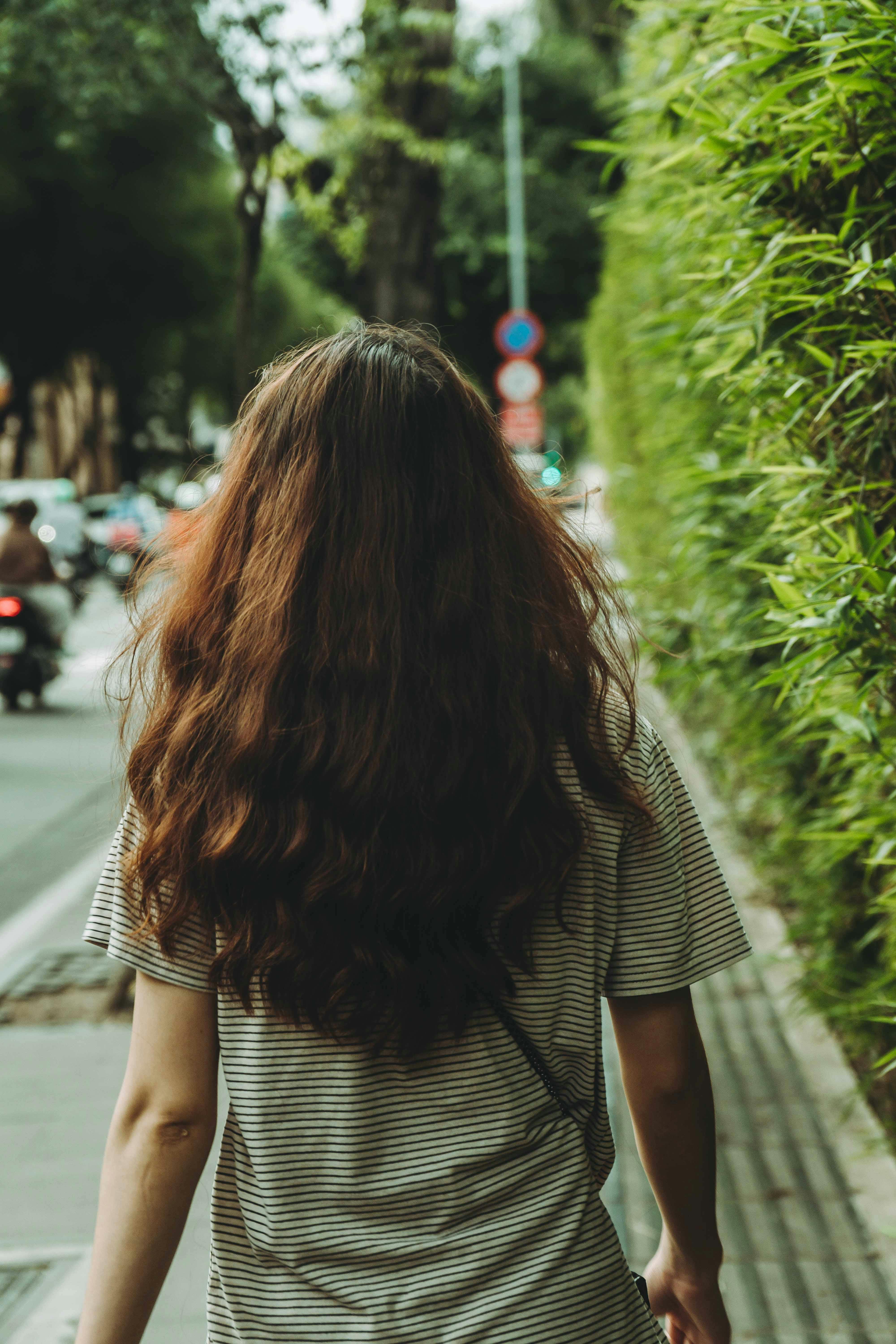 a woman walking down a street with her hair flowing