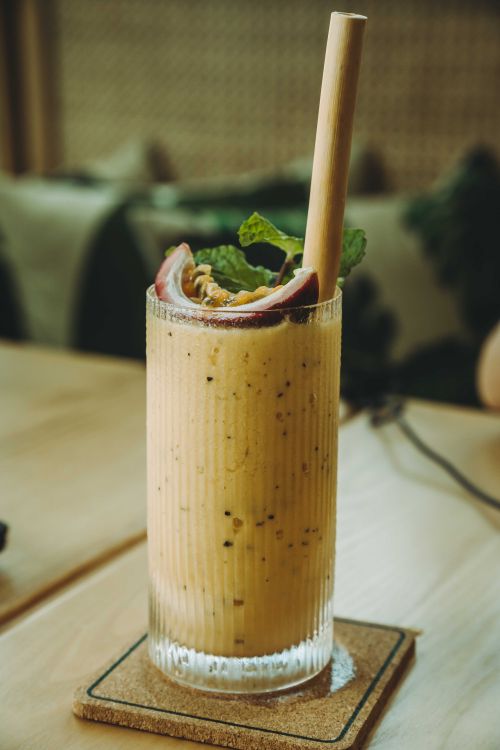 Free Chilled passion fruit smoothie with mint garnish on wooden table in cafe, perfect for summer refreshment. Stock Photo