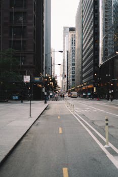 清晨的阳光洒在宁静的城市街道上，两旁摩天大楼林立，捕捉着城市生活的气息