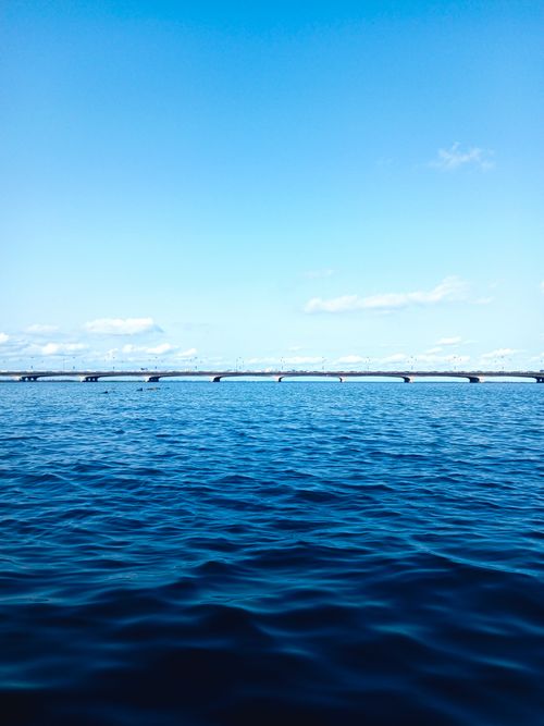 Free A tranquil scene of Lagos Lagoon with a bridge under a clear blue sky, perfect for travel and nature themes. Stock Photo
