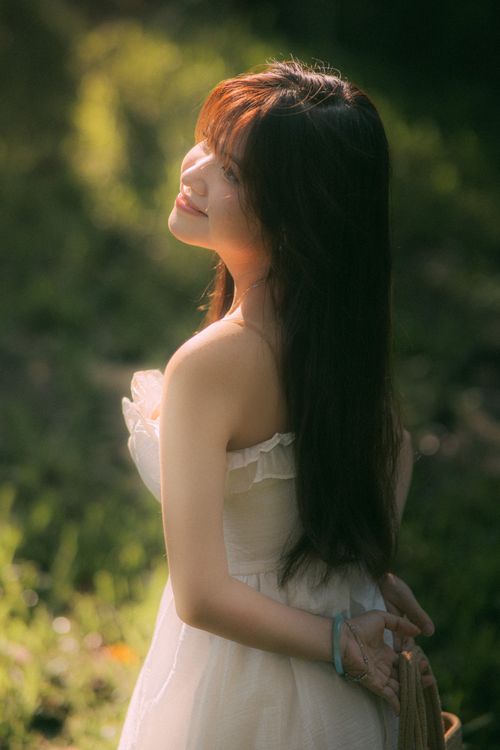 Free A woman in white dress enjoying a sunny day in a lush garden. Stock Photo