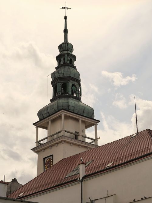 Free View of a historic church tower featuring a clock in a European city against a cloudy sky. Stock Photo