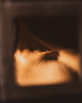 Artistic portrait of a male torso in warm lighting, highlighting collarbone and shadows for an abstract effect.