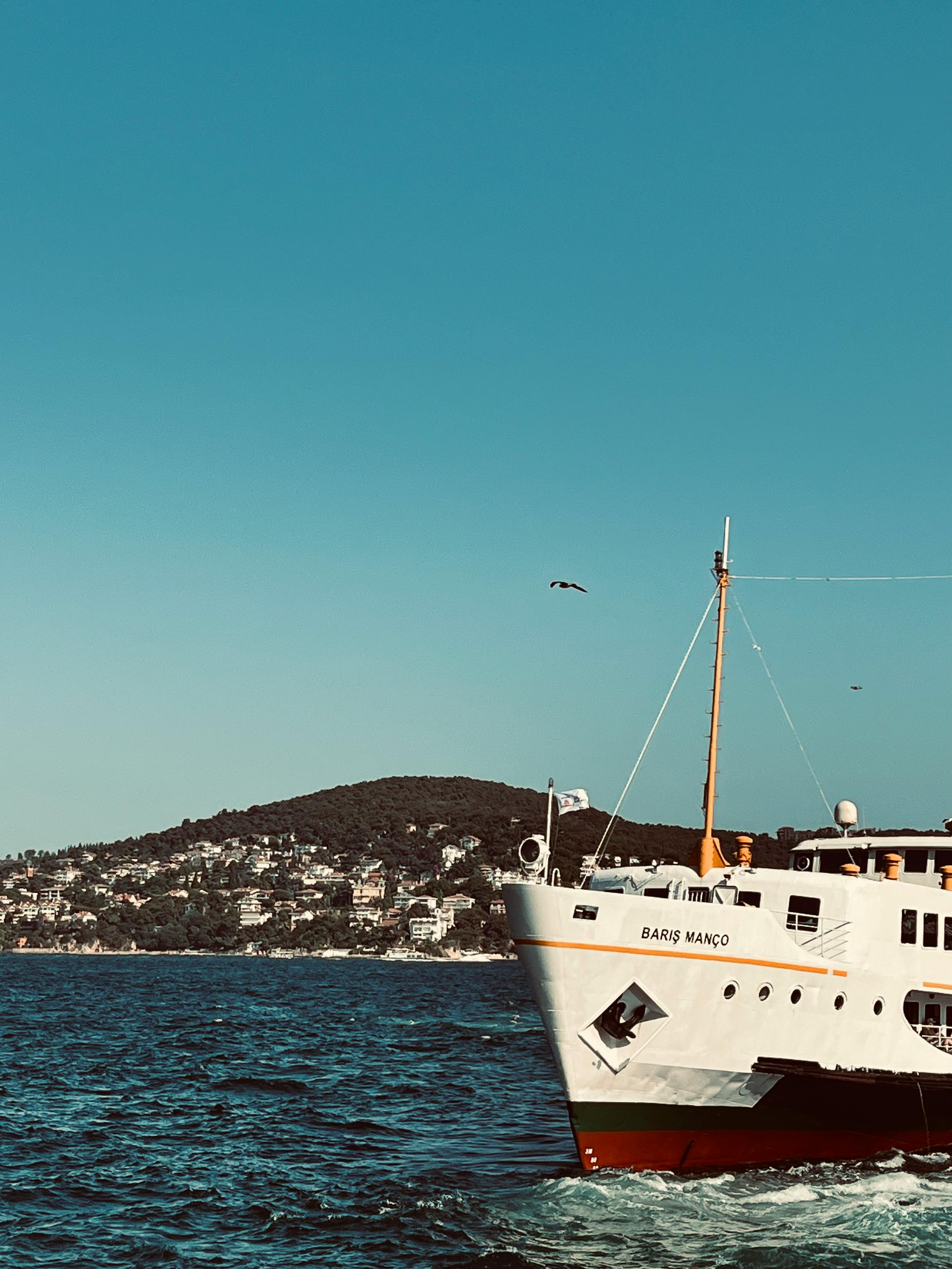 A ferry named Barış Manço sails on a sunny day with an island in the background.